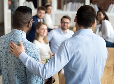 Group of people sat in a room watching a man present stood up