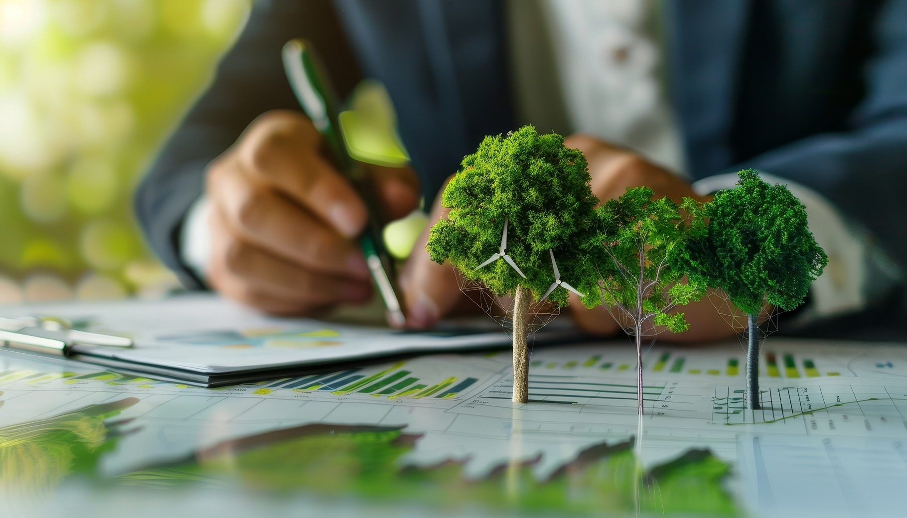 Business professional writing on a clipboard with charts, graphs, and model trees representing sustainability or financial growth