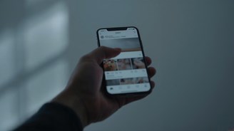 Hand holding a smartphone displaying a social media feed, illustrating the use of social media for accountants