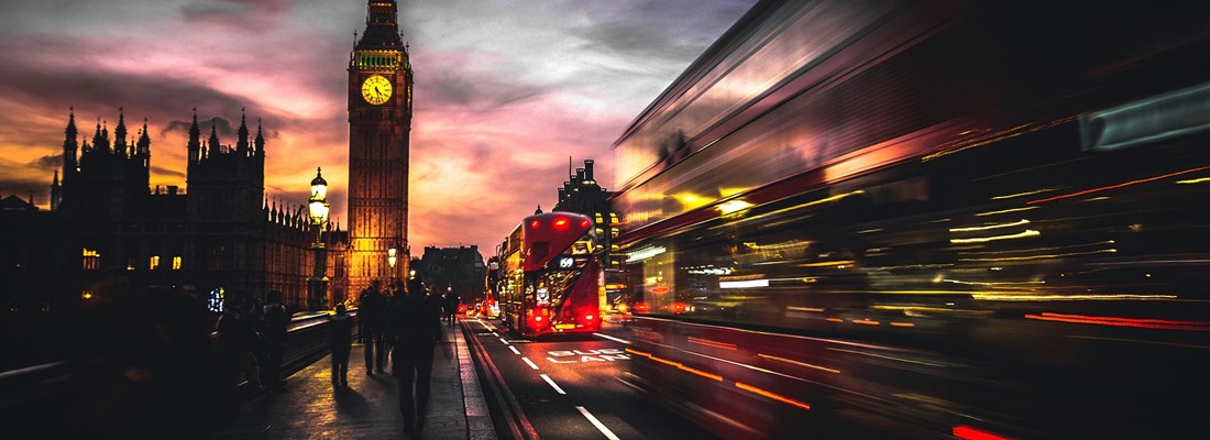 Big Ben and Westminster Bridge at dusk with blurred motion of double-decker buses in London