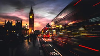 Big Ben and Westminster Bridge at dusk with blurred motion of double-decker buses in London